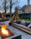 Fire pit is lit in front of a house with a large couch and several pillows Royalty Free Stock Photo