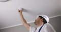 fire safety engineer installing photoelectric smoke detector on house ceiling. home security and fire alarm system