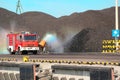 Fire truck spraying water on a black coal stockpile creating a rainbow Royalty Free Stock Photo
