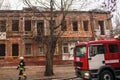 A fire truck is standing next to the The fireman walks next to the fire engine against the ruined building. Selective focus