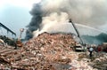 Fire trucks and firefighters fight a mountain of fire in a large mountain of trash