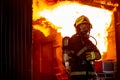 Fire on wall and ceiling in the kitchen behind firefighter man with protective and safety clothes stand with arm-crossed Royalty Free Stock Photo