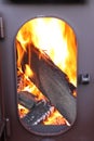 Fire-wood are burning in a fire-chamber of a stove with an opened door