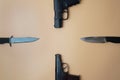 Firearms laid out along a circle. Three guns pistols, army knives close-up on a neutral beige background. copy space