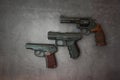 Firearms laid out along the line. Three guns close-up on a gray concrete background. copy space