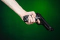 Firearms and murderer topic: human hand holding a gun on a dark green background isolated in studio