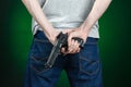 Firearms and murderer topic: man in a gray t-shirt holding a gun on a dark green background isolated in studio