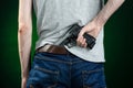 Firearms and murderer topic: man in a gray t-shirt holding a gun on a dark green background in studio