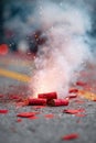 Firecrackers exploding on a street during a festive celebration, surrounded by scattered red paper remnants, creating a Royalty Free Stock Photo