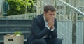 Fired business man sitting frustrated and upset on stairs near office building with box of his belongings. He lost work Royalty Free Stock Photo