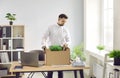 Fired employee standing by his office desk and packing his belongings in a cardboard box Royalty Free Stock Photo