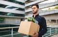 Fired middle eastern manager guy exiting corporate building with box