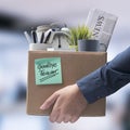 Fired office worker carrying personal belongings in a box