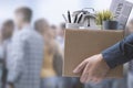 Fired office worker carrying personal belongings in a box