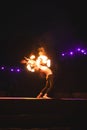 Firedancer performing artful dance under lights in the dark