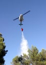 Firefight helicopter dropping water over fire on a forest Royalty Free Stock Photo