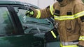 Firefighter beraking glass on car window extricate trapped victim from the car