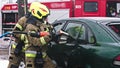 Firefighter beraking glass using jaws of life to extricate trapped victim from the car