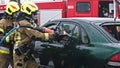 Firefighter beraking glass using jaws of life to extricate trapped victim from the car