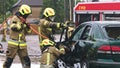 Firefighter beraking glass using jaws of life to extricate trapped victim from the car Royalty Free Stock Photo