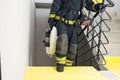 A firefighter climbs the stairs and carries a hose line and equipment for extinguishing fires indoors, front view