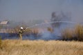 Firefighter extinguishes burning, dry grass from fire hose