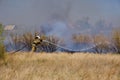 Firefighter extinguishes burning, dry grass from fire hose Royalty Free Stock Photo