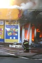 Firefighter extinguishes a fire in a burning building with water from a hose. Hazardous work fireman