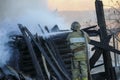 Firefighter extinguishes the fire. Fireman holding hose with water, watering strong stream of burning wooden structure in smoke. Royalty Free Stock Photo