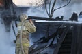 Firefighter extinguishes the fire. Fireman holding hose with water, watering strong stream of burning wooden structure in smoke. Royalty Free Stock Photo