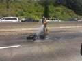 Firefighter extinguishing charred motorcycle on highway