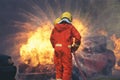 Firefighter fighting with flame using fire hose chemical water foam spray engine. Fireman wear hard hat, body safe suit uniform Royalty Free Stock Photo