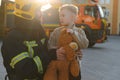 Firefighter holding child boy to save him in fire and smoke,Firemen rescue the boys from fire Royalty Free Stock Photo