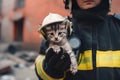 the firefighter is holding on hand a little kitten , he took him out of the fire. Generative AI