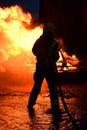 Firefighter hoses down a fire amid strong flames