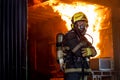 Firefighter man with protective and safety clothes stand with arm-crossed in front of fire on wall and ceiling in the kitchen Royalty Free Stock Photo