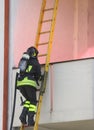 Firefighter with oxygen cylinder climbing a wooden ladder Royalty Free Stock Photo