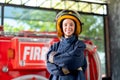 Firefighter with protective clothes stand with confidence action and smile in front of fire truck. She also smile with happy and Royalty Free Stock Photo