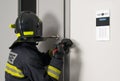 Firefighter in protective uniform and helmet opens the closed door Royalty Free Stock Photo