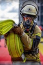 Firefighter in a SCBA carrying a bright yellow fire hose in a professional manner