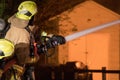 Firefighter spray water on house fire with hose. Royalty Free Stock Photo