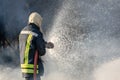 Firefighter spraying water from big water hose to prevent fire