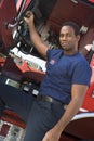 A firefighter standing by the cab of a fire engine