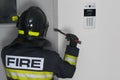 A firefighter tries to open the iron entrance door in the entrance, with a crowbar, close-up