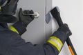 A firefighter tries to open the iron entrance door in the entrance with a hatchet, close-up