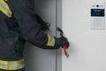 A firefighter tries to open the iron entrance door with an intercom in the entrance with a crowbar, close-up