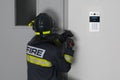 A firefighter tries to open the iron front door with a crowbar