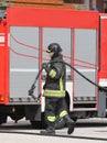 firefighter with helmet who puts away the hose after the interve Royalty Free Stock Photo