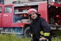 Firefighter in uniform with red helmet standing in front of fire engine, emergency services, rescue operation, fire Royalty Free Stock Photo