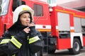 Firefighter in uniform using portable radio set near fire truck Royalty Free Stock Photo